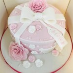Pink cake with white bow and pink flowers