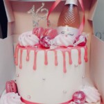 Pink and white birthday cake with pink Champaign bottle