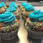 Cupcakes with rainbow sprinkles topped with blue frosting